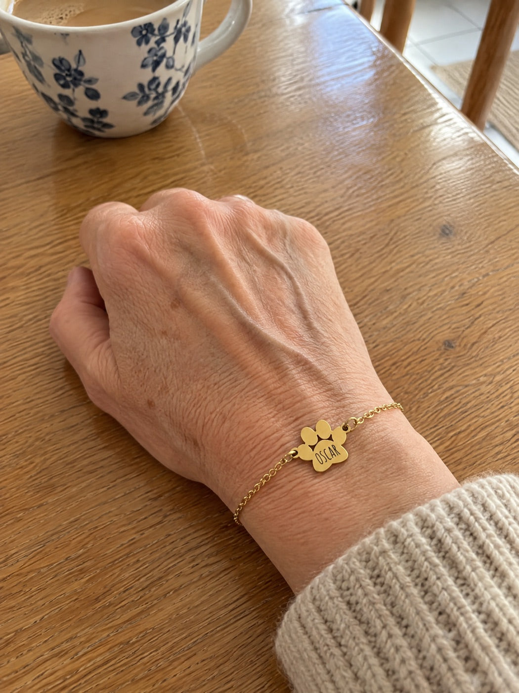 Un bijou fin porté au poignet, avec une petite patte dorée gravée d'un prénom